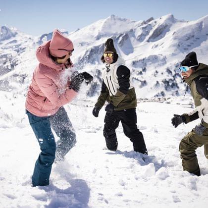 Three friends having a snowball fight in a snowy alpine mountain landscape
